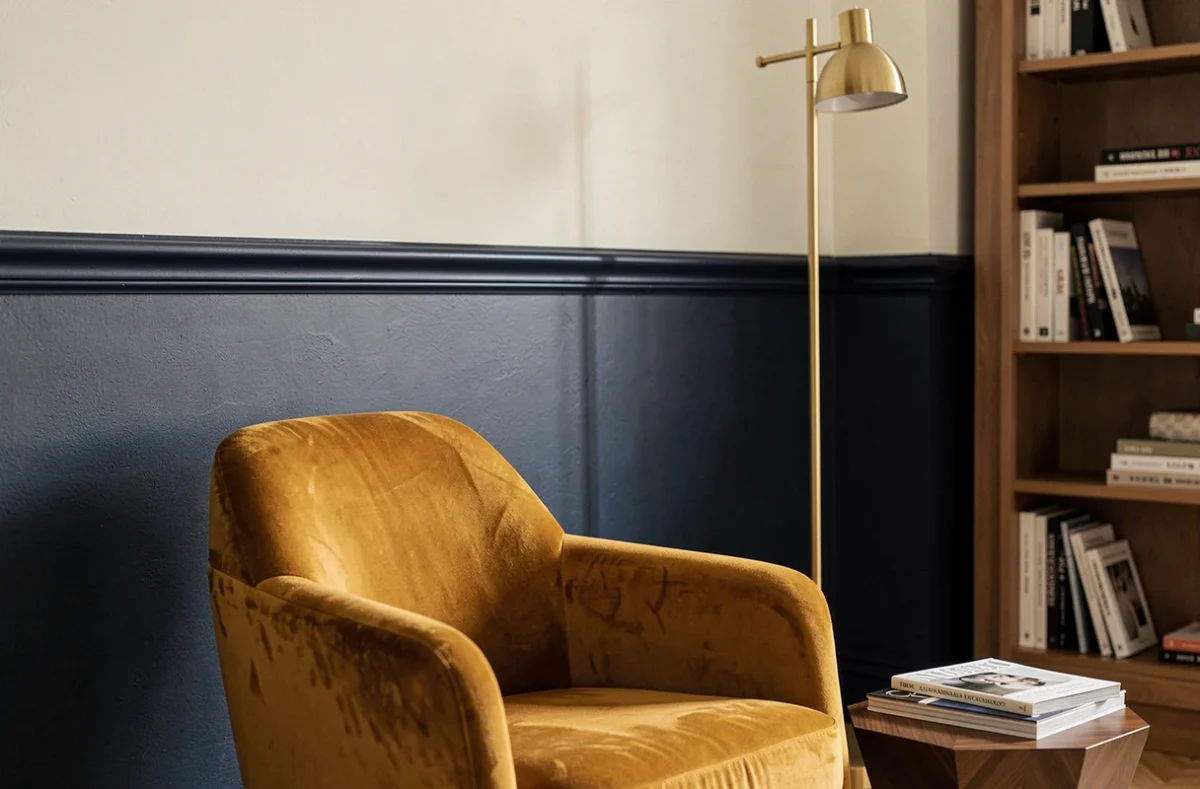 Coin salon élégant avec technique de peinture bicolore bleu marine et blanc crème, fauteuil velours ocre et lampe laiton style mid-century