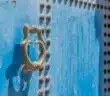 grey door knocker on blue wooden door with rivets