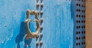 grey door knocker on blue wooden door with rivets